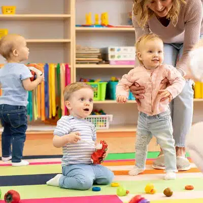 teacher helping toddlers stand